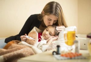 Portrait of caring mother kissing sick daughter in head