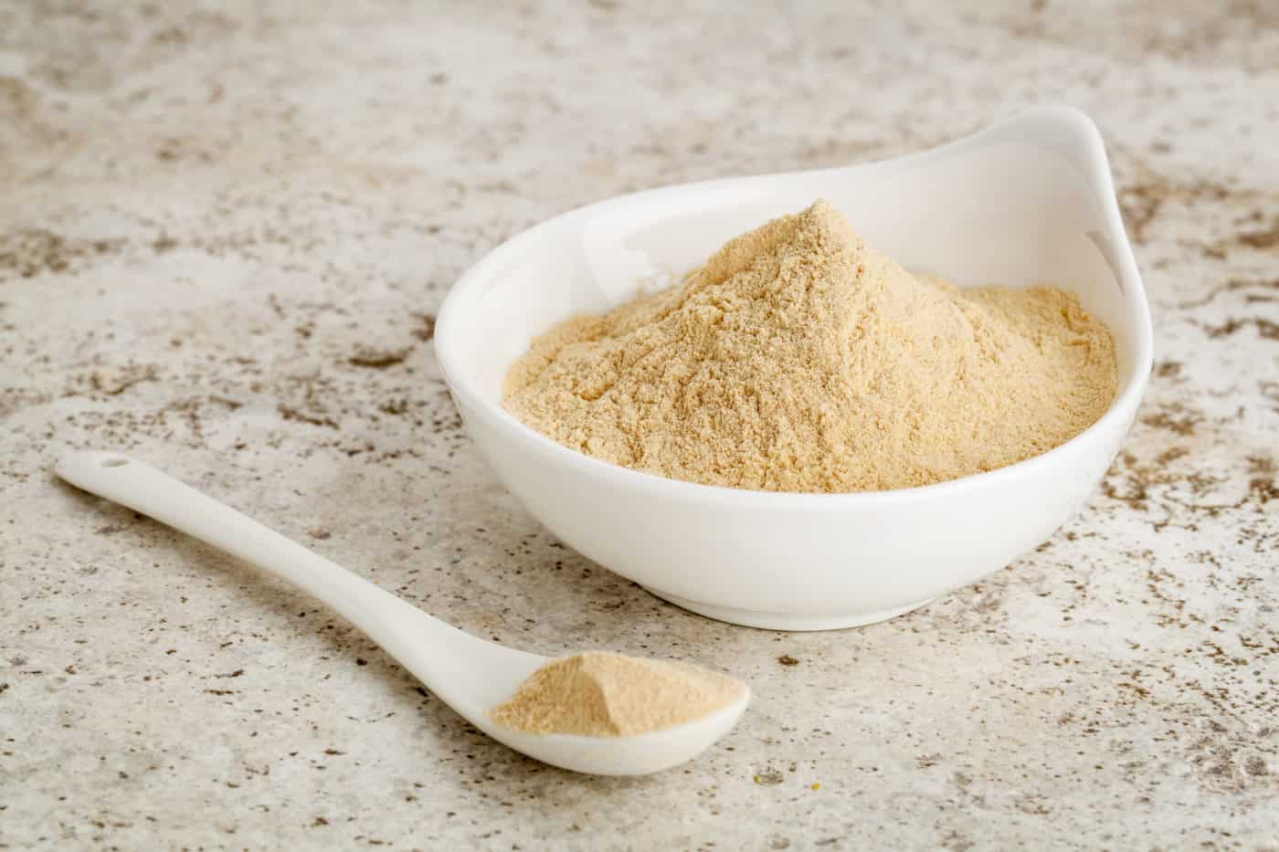 maca root powder - a small bowl with a spoon against ceramic tile surface
