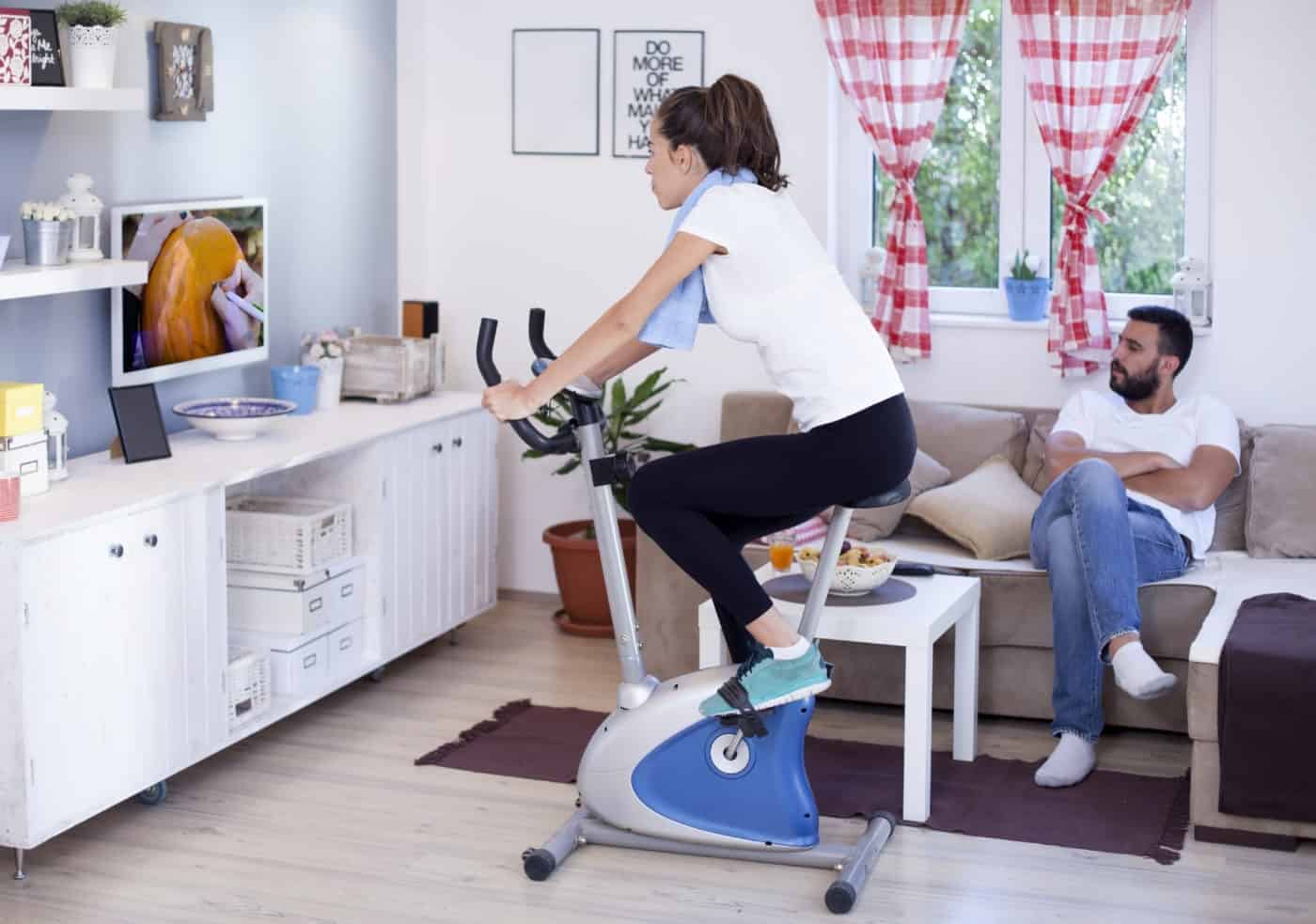 Sporty woman training on exercise bike in the living room